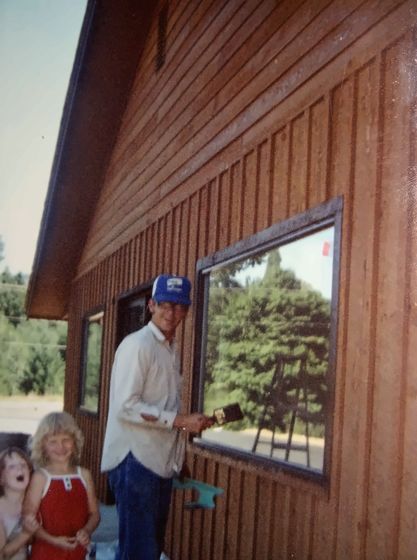 Working on the siding, with a child nearby