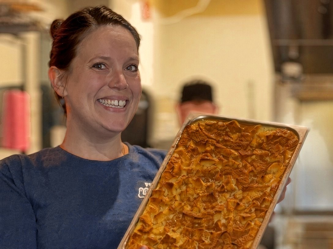 Holding a fresh tray of bread pudding in the kitchen